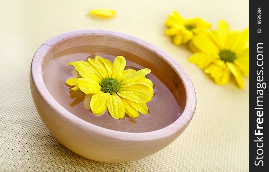 Yellow flowers in wooden bowl. Spa theme