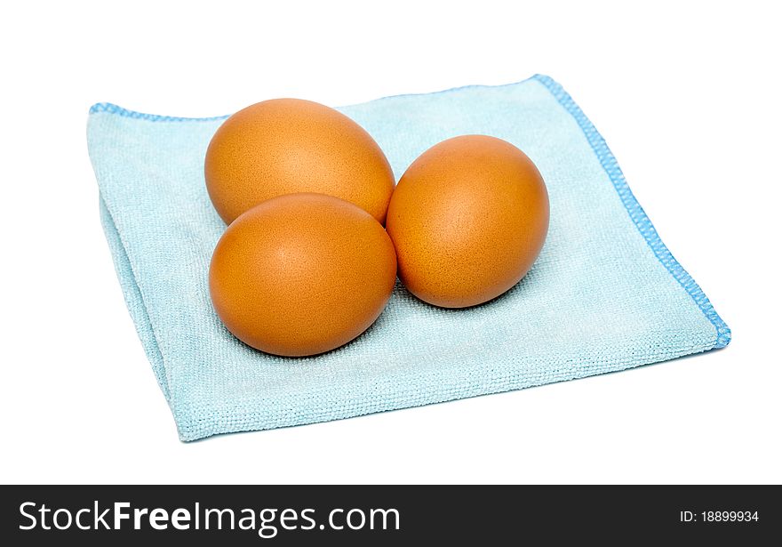 Three brown eggs on blue napkin, isolated