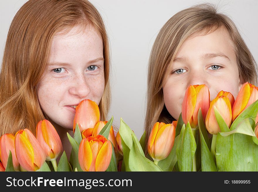 Two young girls are holding pink orange tulips