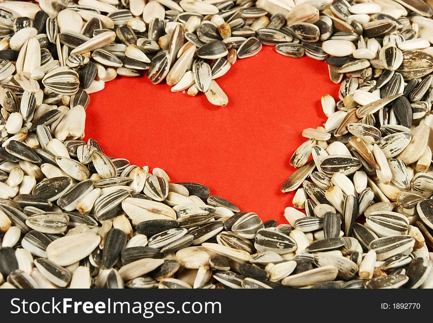 Heart made of seeds with red background