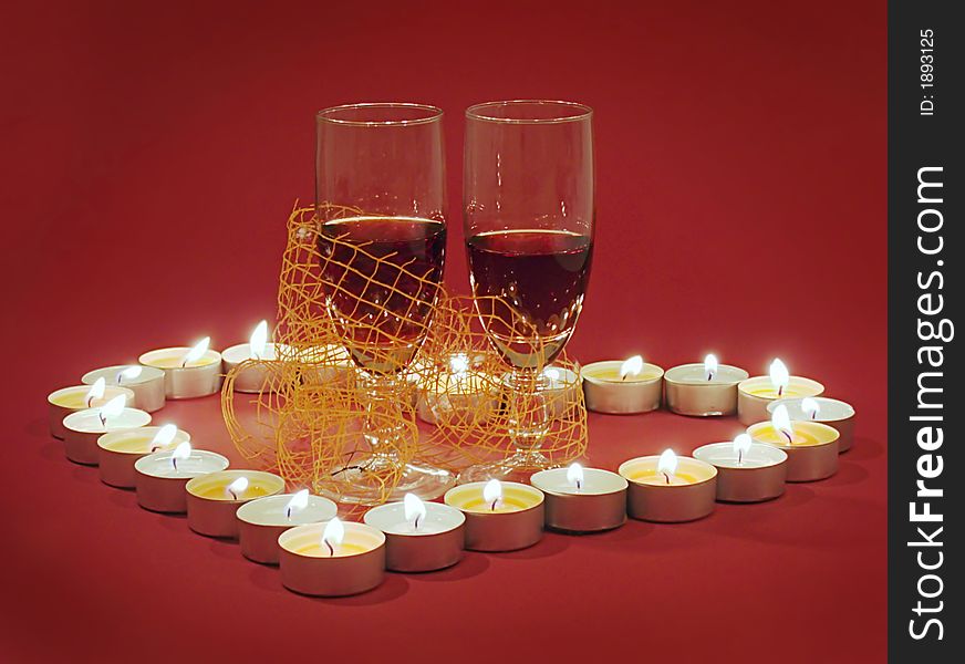 Red romantic Valentine's Day composition with two glass of wine in the center of candle burn heart. Red romantic Valentine's Day composition with two glass of wine in the center of candle burn heart.