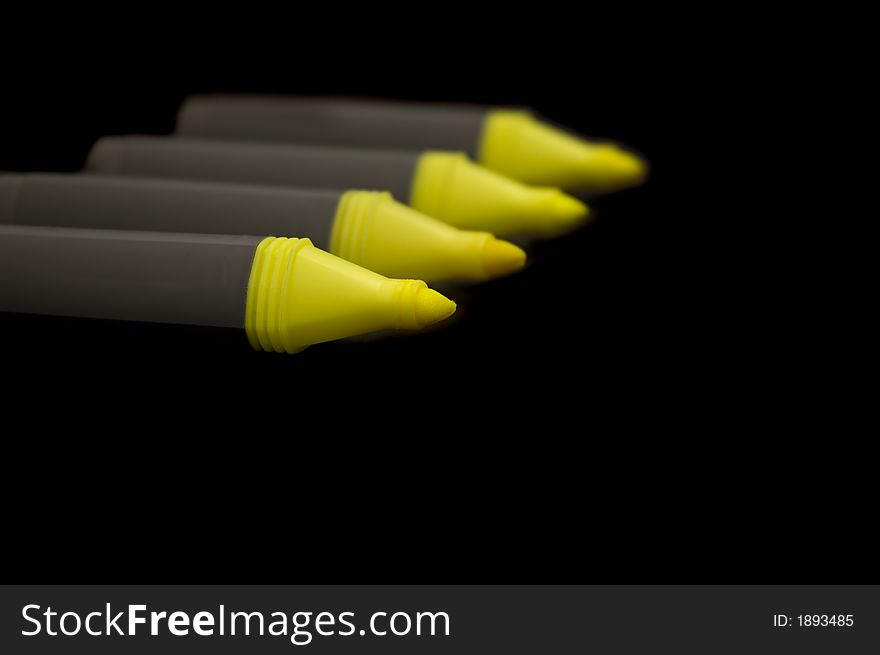 Four yellow highlighter pens isolated on black