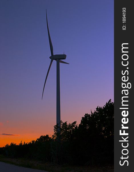 Wind farm at dusk with trees in shadows