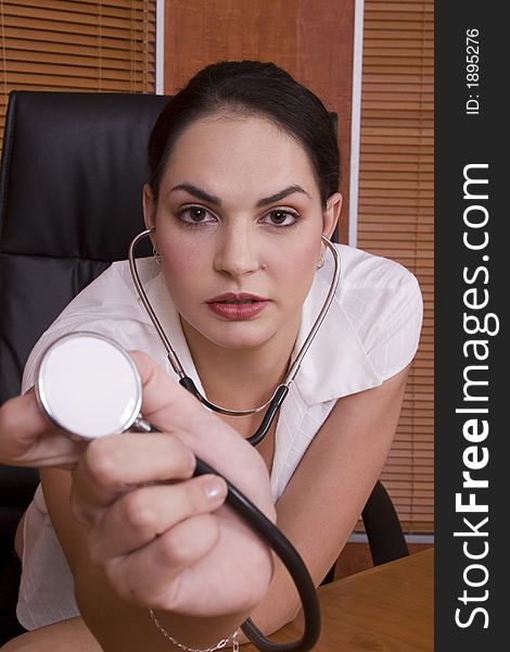 Brunette doctor holding the stethoscope to the camera. Brunette doctor holding the stethoscope to the camera