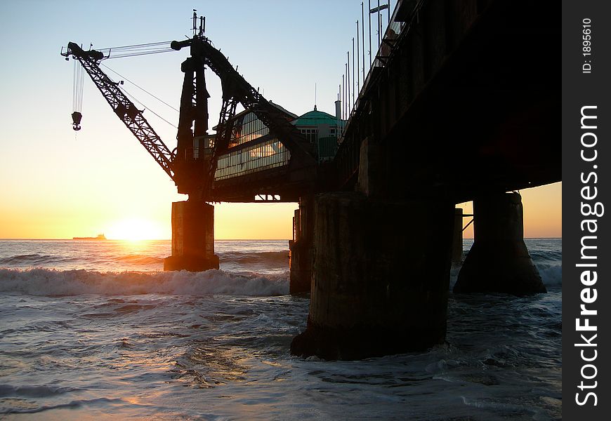 A sunset at a Chilean beach with an abandoned industrial crane. A sunset at a Chilean beach with an abandoned industrial crane
