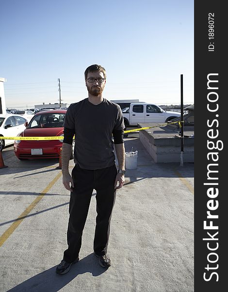 Man wearing tee shirt standing roof top parking lot with cars in the background. Man wearing tee shirt standing roof top parking lot with cars in the background.