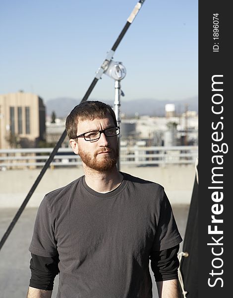 Man wearing tee shirt standing in the sun roof with city in the background. Man wearing tee shirt standing in the sun roof with city in the background.