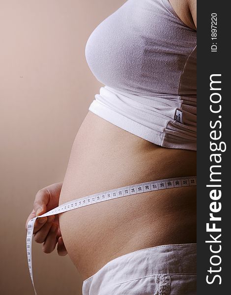 Pregnant woman measuring her belly while standing. Pregnant woman measuring her belly while standing