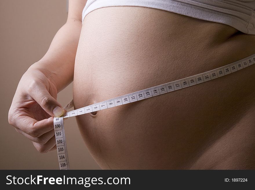 Pregnant woman measuring her belly while standing. Pregnant woman measuring her belly while standing