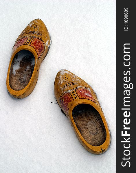 A pair of dutch wooden shoes are left in the snow. A pair of dutch wooden shoes are left in the snow.