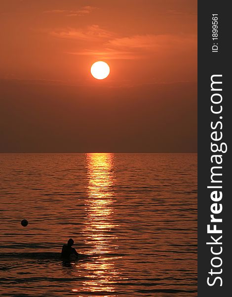 A boy throwing a ball in background of a beautiful sunset. A boy throwing a ball in background of a beautiful sunset