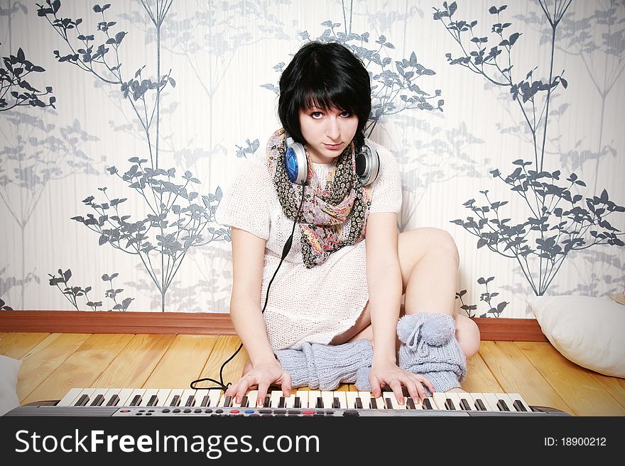 Cute young woman with headphones playing on piano, studio shot. Cute young woman with headphones playing on piano, studio shot