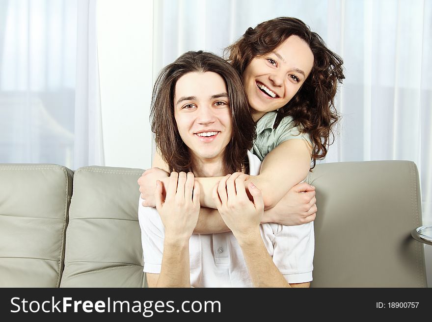 Loving young couple with arms around and smiling. Indoors. Loving young couple with arms around and smiling. Indoors