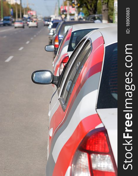 A road with parked cars, focus is on the side mirror of the car in the foreground.