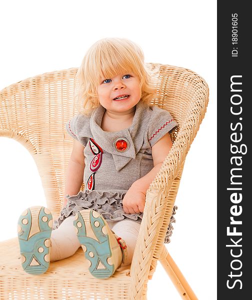 Pretty little girl sitting on wicker amchair