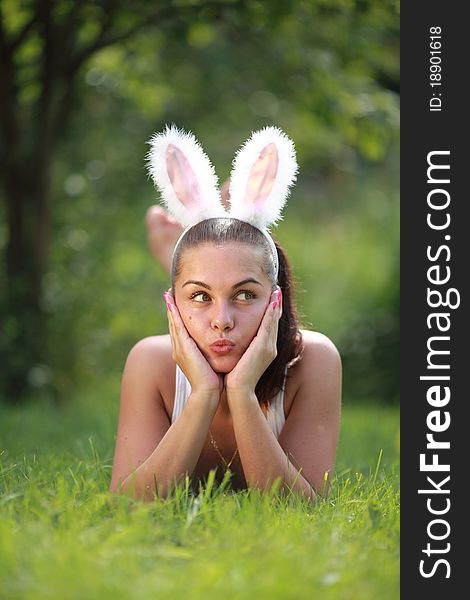 Woman with funny rabbit ears lies on a grass outdoors