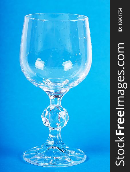 Empty wineglass with drops over blue background