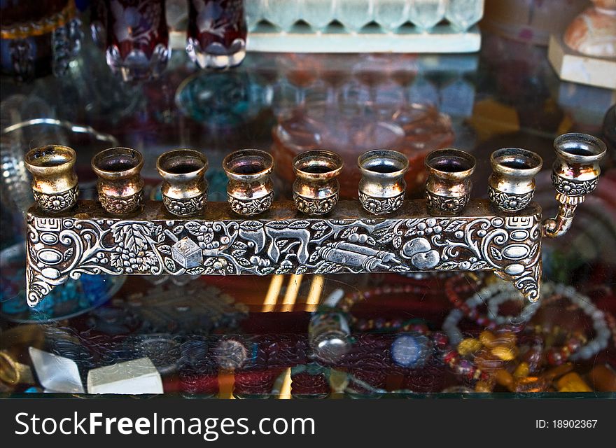 Antique decorative candlestick for Hanukkah holyday.Simple form, decorated metal, hebrew letters, colorful background.Jerusalem fleamarket. Antique decorative candlestick for Hanukkah holyday.Simple form, decorated metal, hebrew letters, colorful background.Jerusalem fleamarket.