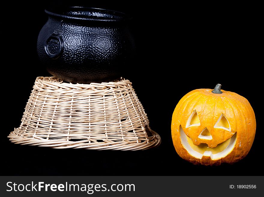 A pumpkin, harvest basket and a cauldron on black. A pumpkin, harvest basket and a cauldron on black.