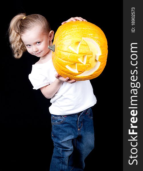 A girl is stuggling to hold up her pumpkin. The face is sideways. A girl is stuggling to hold up her pumpkin. The face is sideways.