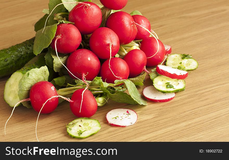 Radish bunch and cucumber on a wooden surface. Radish bunch and cucumber on a wooden surface