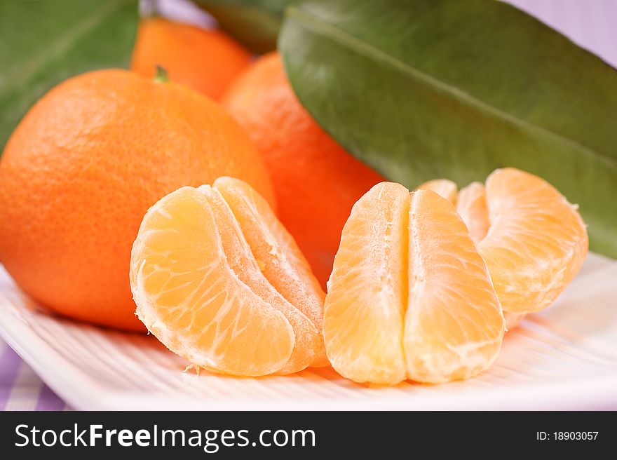 Whole and sectioned clementines over a white dish. Selective focus, extra-shallow DOF.