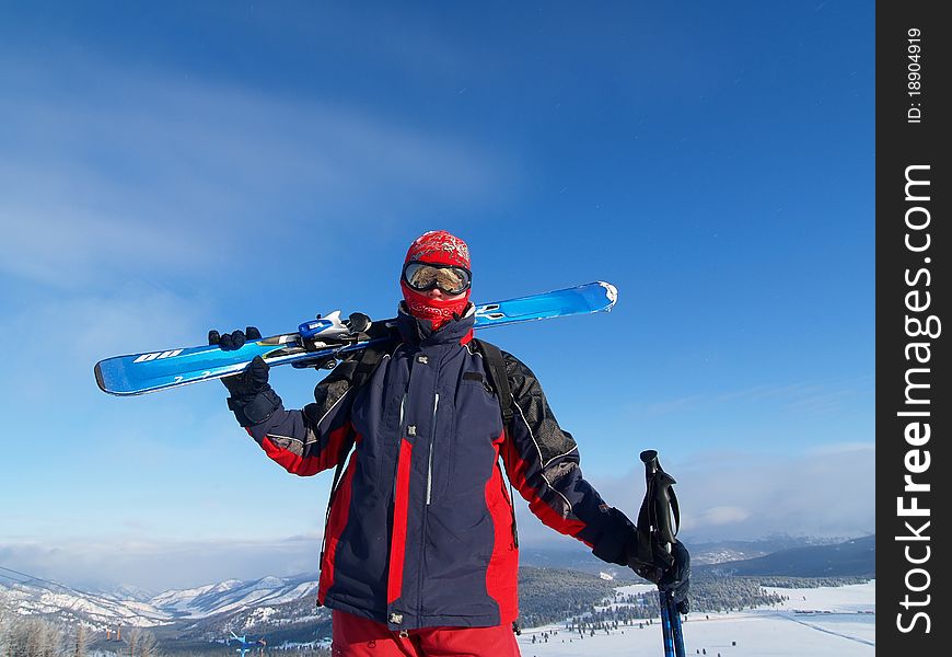 Skier in the mountains with skis on his shoulder