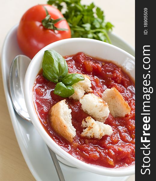 Bowl of tomato soup with bread crouton and basil