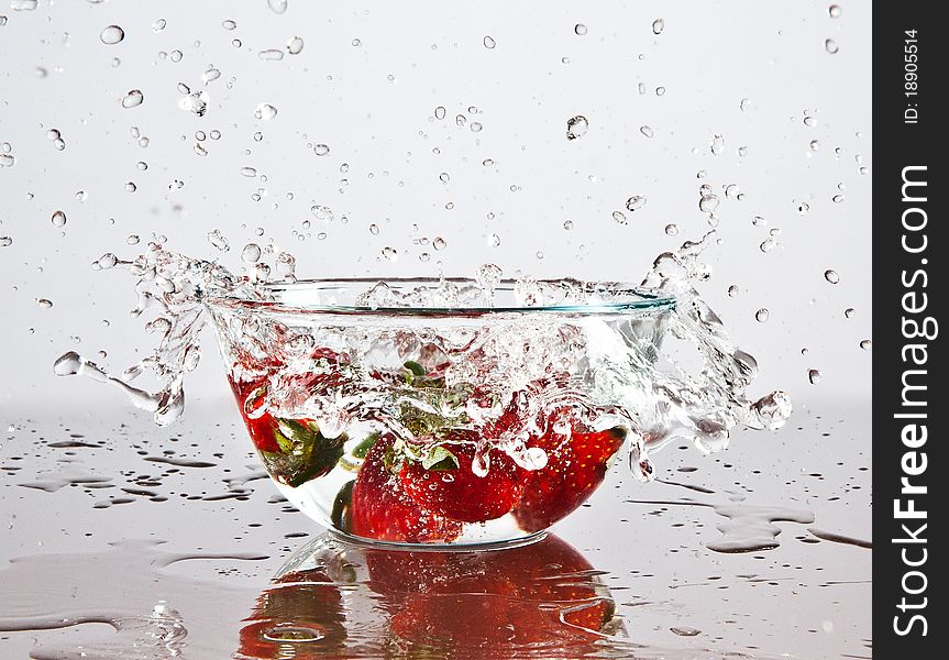 Water splashing over strawberries fallen into it. Water splashing over strawberries fallen into it