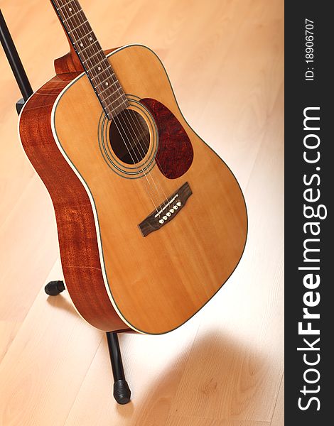 Brown guitar on black stand; neutral background. Brown guitar on black stand; neutral background