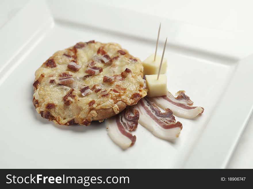 Freshly baked pastry with bacon and cheese on a square ceramic white plate