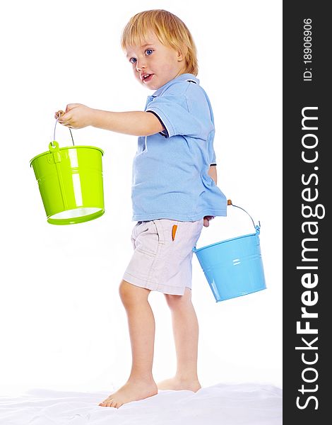Little cute boy holding green and blue buckets isolated over white background. Little cute boy holding green and blue buckets isolated over white background