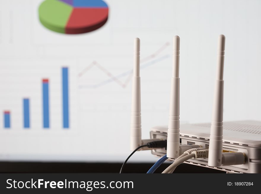 WIFI business network concept. Wireless router with plugs on foreground and business diagrams on background. Selective focus on router. WIFI business network concept. Wireless router with plugs on foreground and business diagrams on background. Selective focus on router