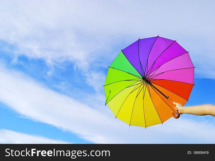 Multicolored umbrella and clouds sky