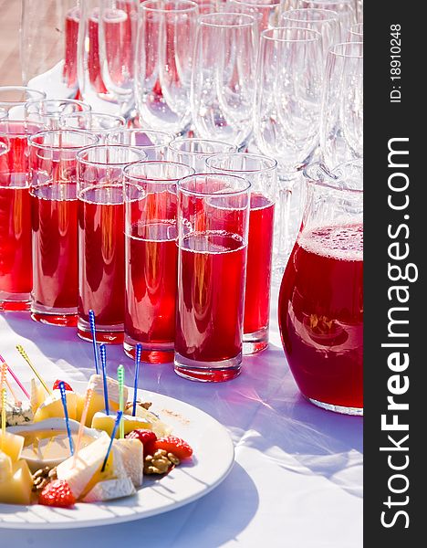 Transparent glasses with a red drink on a white table.