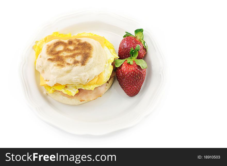 A hot ham, cheese and egg, English muffin on a white plate with white background, top view with white background. A hot ham, cheese and egg, English muffin on a white plate with white background, top view with white background