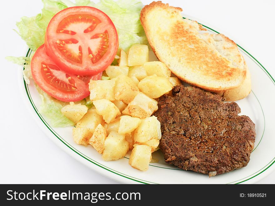 A delicious juicy hamburger steak with seasoned diced potatoes, sliced tomatoes and toasted bread on a platter, top view, white background. A delicious juicy hamburger steak with seasoned diced potatoes, sliced tomatoes and toasted bread on a platter, top view, white background