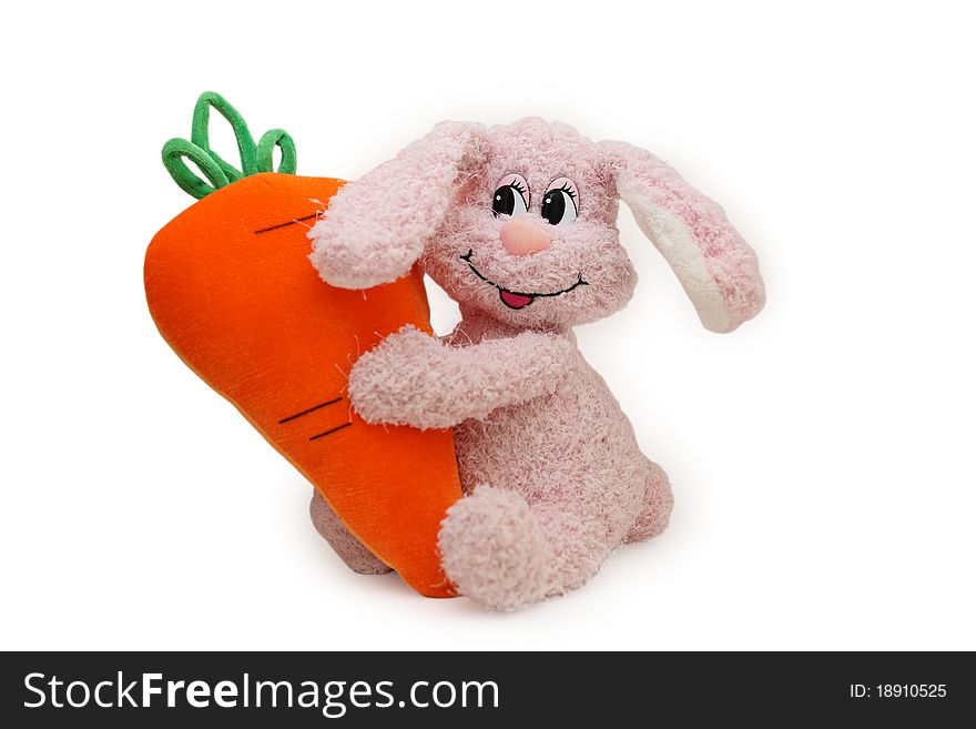 The toy pink rabbit embraces the big carrot. The toy pink rabbit embraces the big carrot