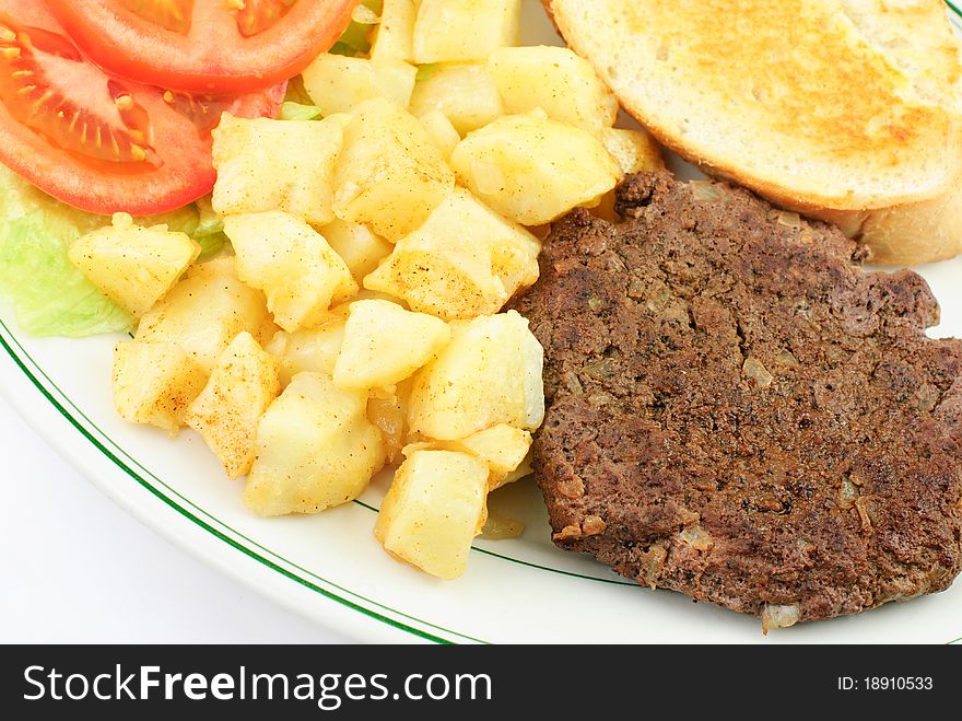 Delicious hamburger steak with onions, diced seasoned potatoes, closeup. Delicious hamburger steak with onions, diced seasoned potatoes, closeup