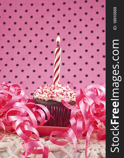 A birthday cupcake with one lit candle, selective focus, low key. A birthday cupcake with one lit candle, selective focus, low key