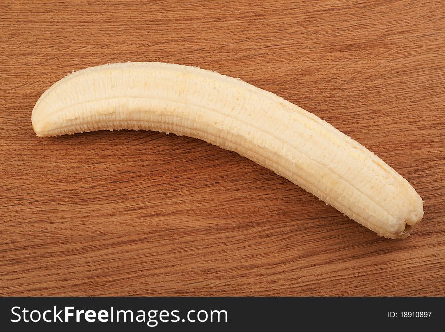 Ripe peeled banana on a wooden background