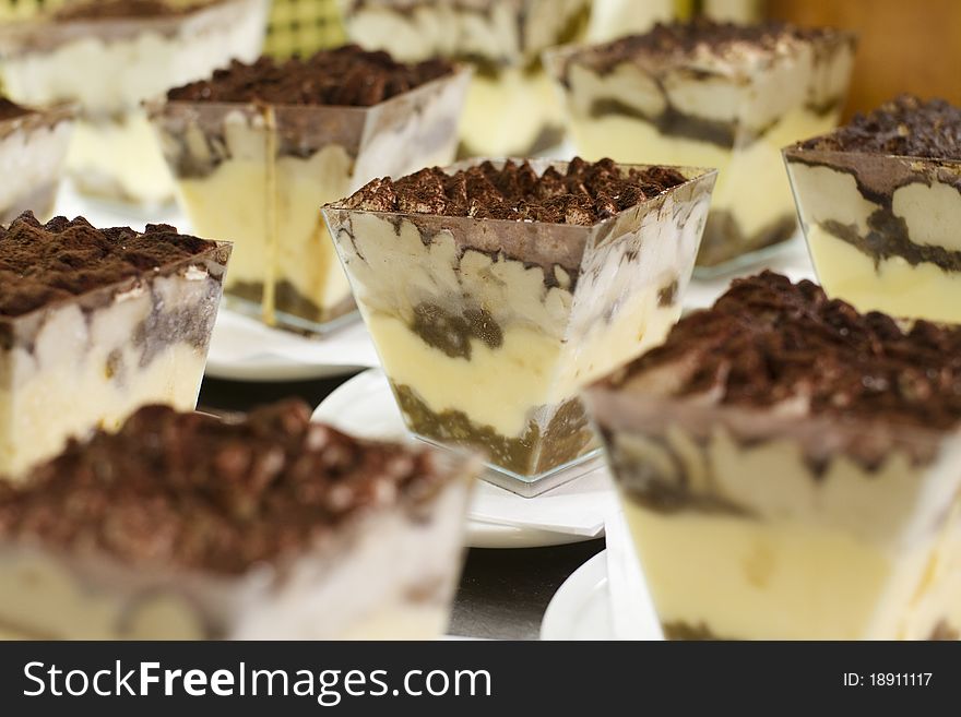 Close up of a TiramisÃ¹, on focus at centre of the photo, and others one out of focus around