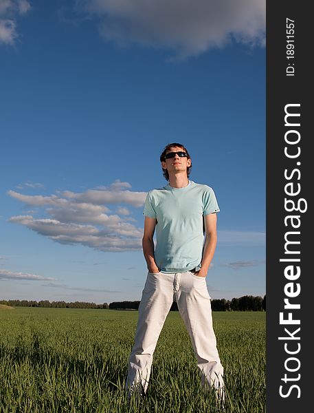 Young man standing in the green grass field. Young man standing in the green grass field