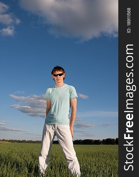 Young man standing in the green grass field. Young man standing in the green grass field