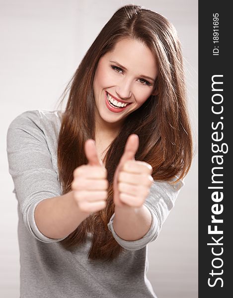 Portrait of beautiful brunette woman isolated on natural background, showing thumbs up