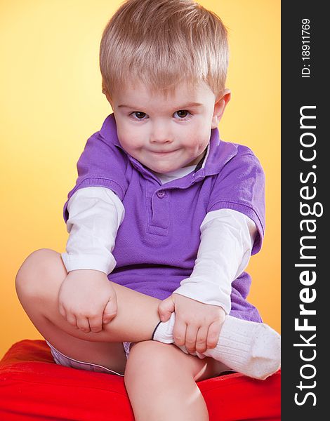 Happy smiling little boy holding leg with hands