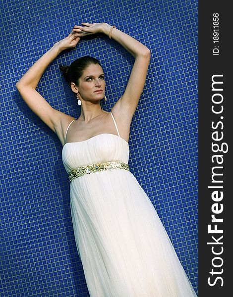 Beautiful brunet bride in wedding dress standing by the blue wall. Beautiful brunet bride in wedding dress standing by the blue wall