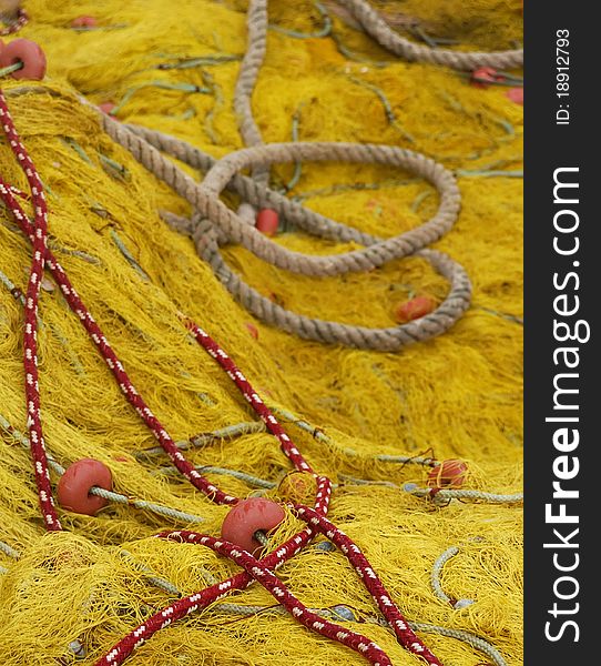 Detail image of a fishing net in front and some ropes on the back. Detail image of a fishing net in front and some ropes on the back