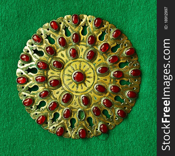 Middle-Asian vintage buckle for east dressing gown. Silver, gilding, semi-precious stones, east ornament. Isolated on dark green woollen cloth. Middle-Asian vintage buckle for east dressing gown. Silver, gilding, semi-precious stones, east ornament. Isolated on dark green woollen cloth.