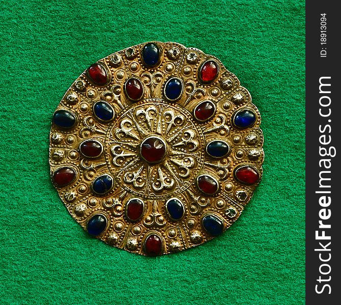 Middle-Asian vintage buckle for east dressing gown. Silver, gilding, semi-precious stones, east ornament. Isolated on dark green woollen cloth. Middle-Asian vintage buckle for east dressing gown. Silver, gilding, semi-precious stones, east ornament. Isolated on dark green woollen cloth.